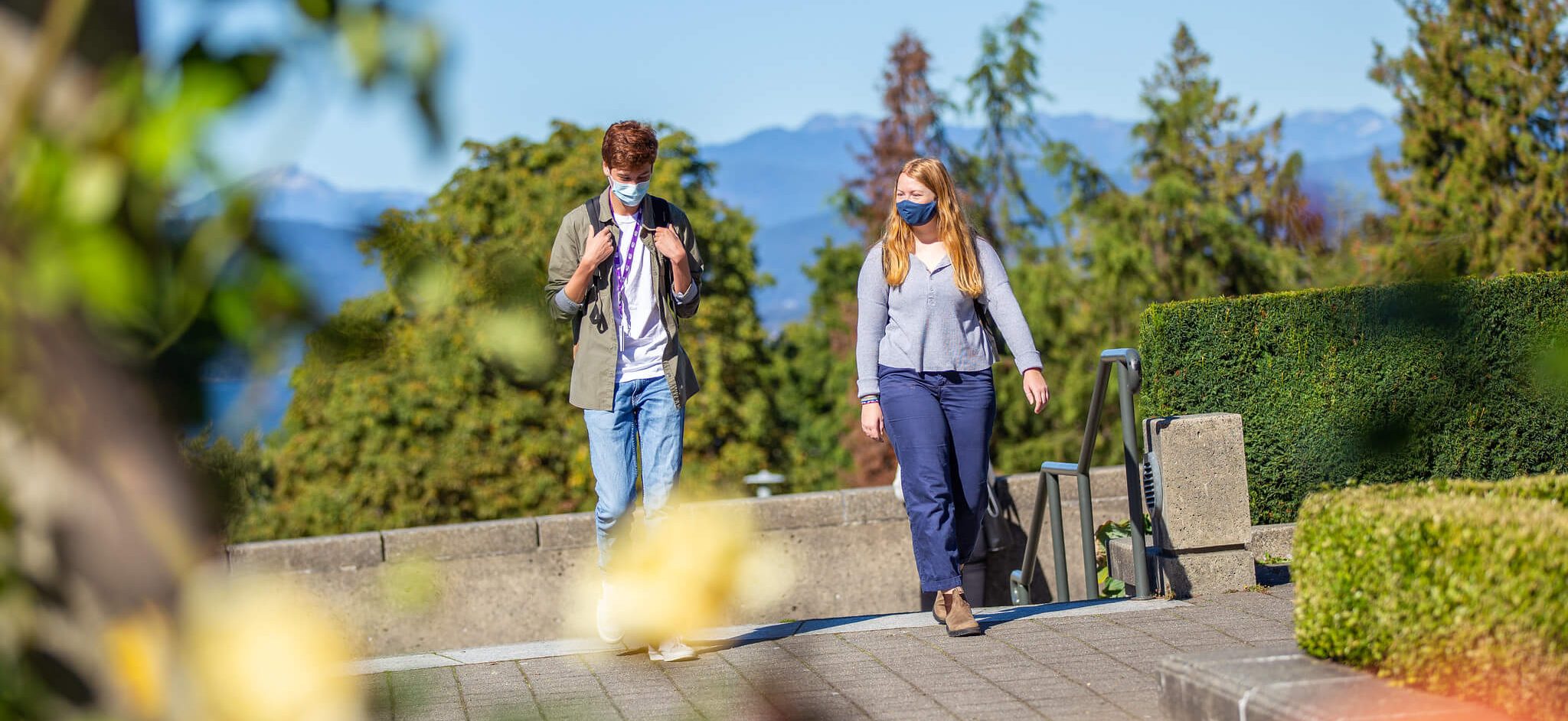 2 students wearing face masks walk through the UBC Vancouver campus